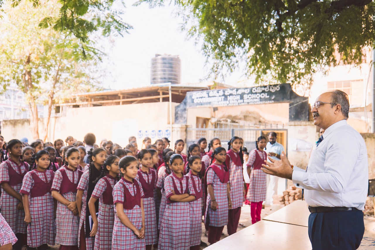 A speaker addressing students in a school courtyard